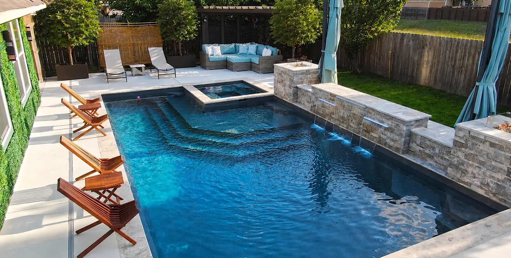 Custom fiberglass pool with integrated spa and waterfall in a Colorado backyard